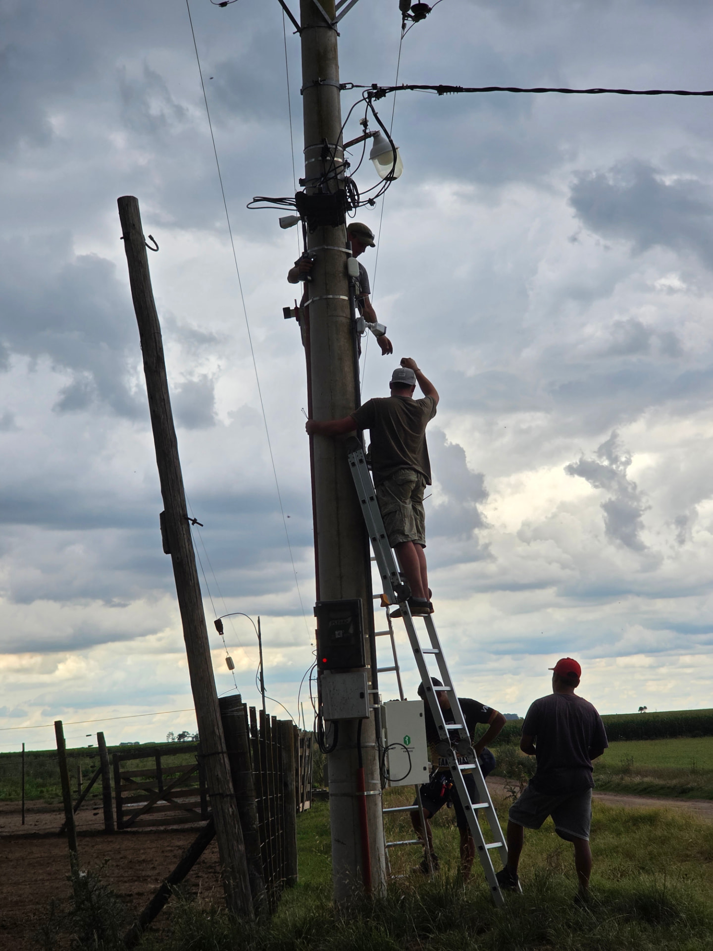 Equipo técnico instalando equipamiento sobre poste en zona rural